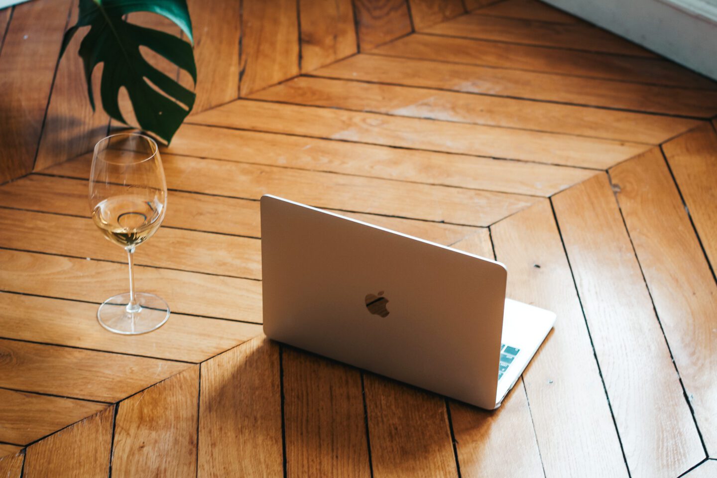 Move to france and work in wine. Computer with wine glass on the floor of a Paris apartment